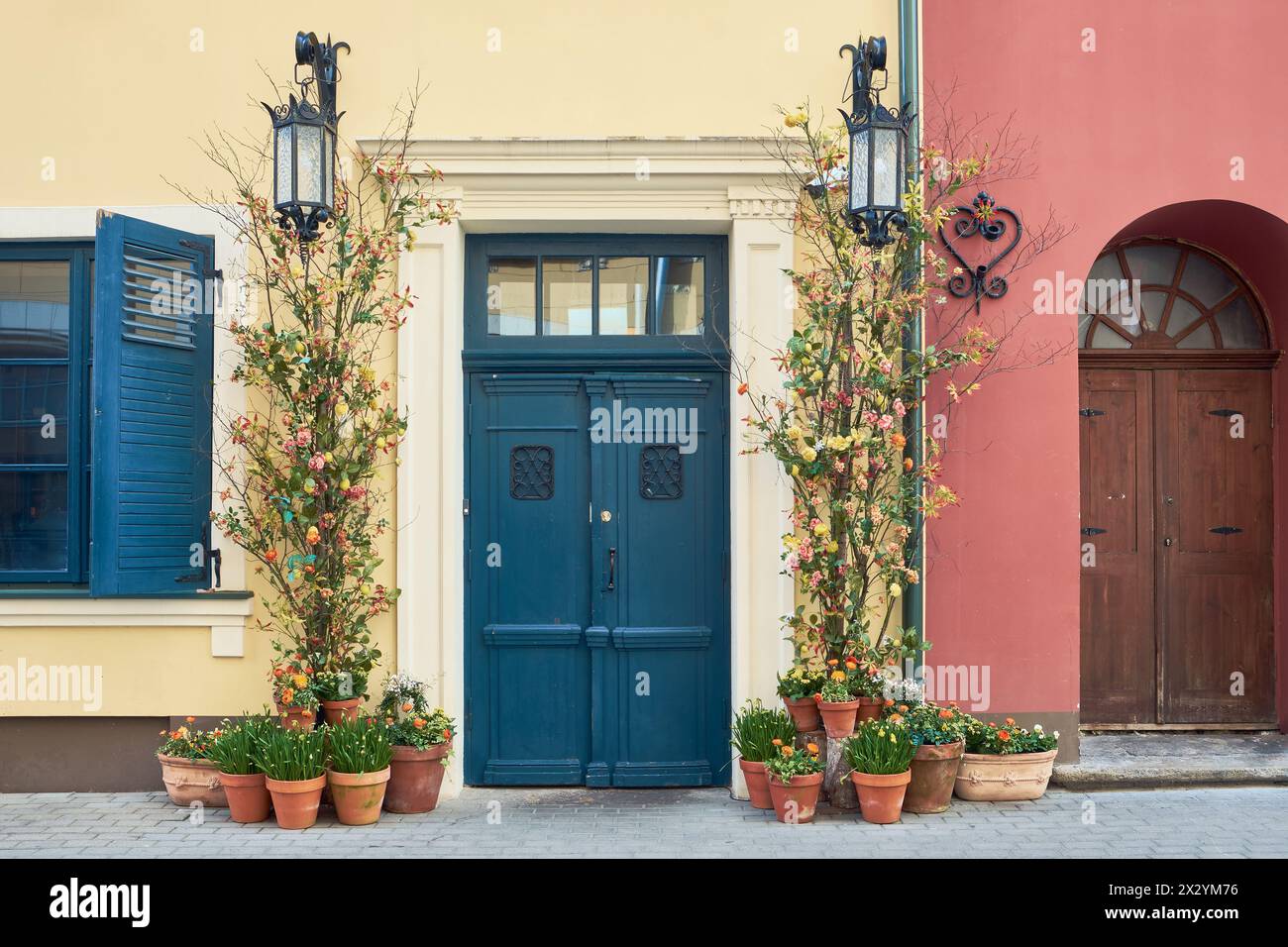 Porte d'entrée vintage sur une ancienne façade de bâtiment décorée avec des fleurs et des fleurs de printemps en pots. Banque D'Images