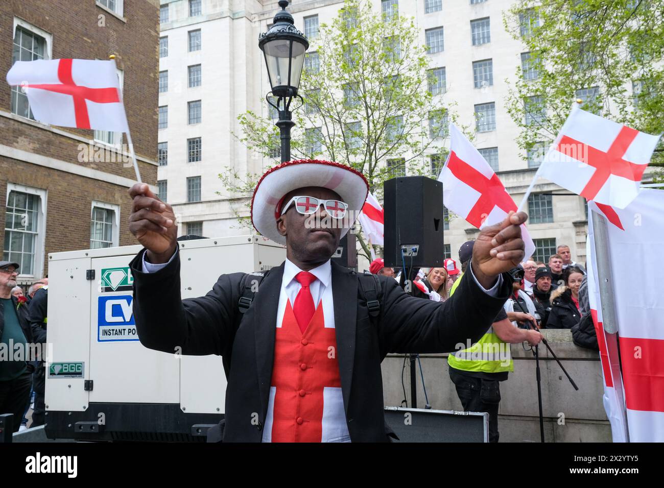 Londres, Royaume-Uni, 23 avril 2024. Un homme porte St rouge et blanc et agite deux drapeaux St George. Un rassemblement et un rassemblement organisés pour célébrer le saint patron de l'Angleterre - et aussi une protestation partielle, ont été suivis par une grande foule de patriotes, de supporters de football et d'autres, portant des drapeaux rouges et blancs et certains en costume. Crédit : onzième heure photographie/Alamy Live News Banque D'Images
