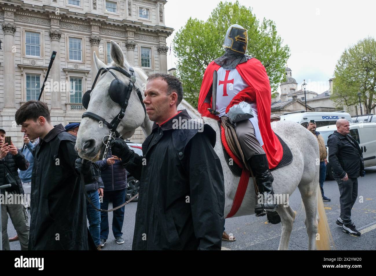 Londres, Royaume-Uni, 23 avril 2024. Un homme habillé en chevalier monte un cheval gris le long de Whitehall. Un rassemblement de la Saint-Georges, en partie une célébration - et en partie une manifestation a été assisté par une grande foule de patriotes, de supporters de football et d'autres, portant des drapeaux rouges et blancs et certains en costume. Crédit : onzième heure photographie/Alamy Live News Banque D'Images