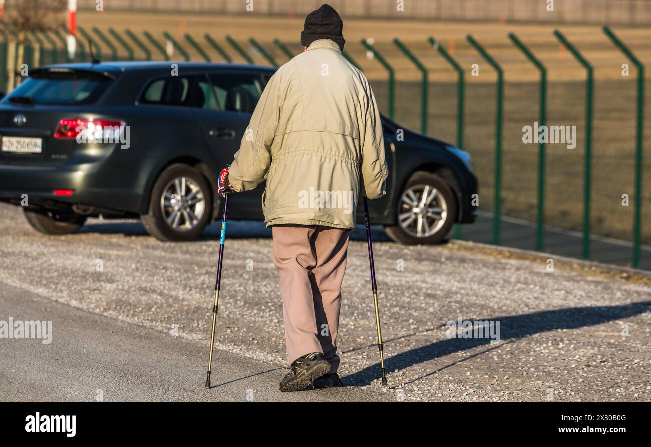 Oberglatt, Schweiz - 25. Januar 2022 : Ein Rentner spaziert mit Gehstöcke auf einer Strasse und geniesst den Tag. Banque D'Images