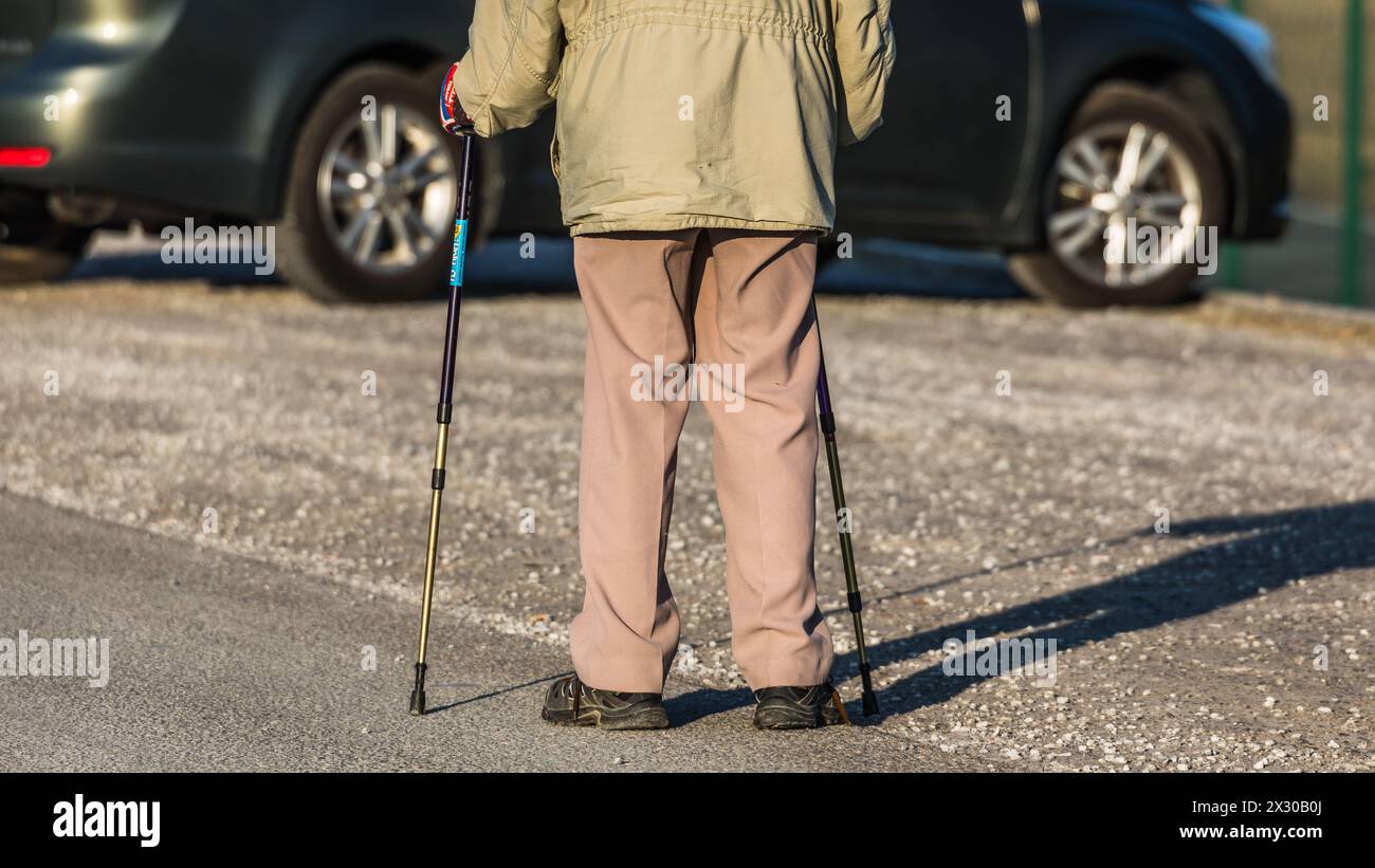 Oberglatt, Schweiz - 25. Januar 2022 : Ein Rentner spaziert mit Gehstöcke auf einer Strasse und geniesst den Tag. Banque D'Images