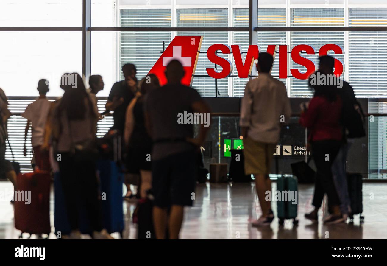 Reisende laufen am Flughafen Zürich vor einem grossen logo von Swiss International Airlines durch. (Zürich, Schweiz, 16.07.2022) Banque D'Images