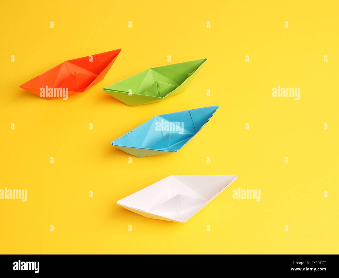 Quatre bateaux en papier différents sur fond jaune, concept de travail d'équipe Banque D'Images