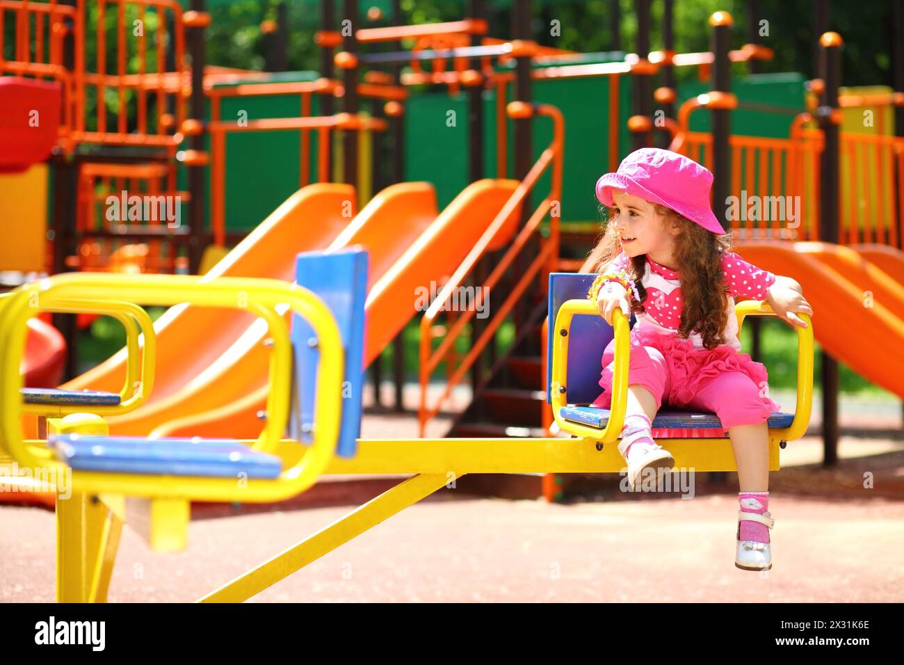 Petite fille souriante dans un chapeau rose tourbillonne sur le rond-point Banque D'Images