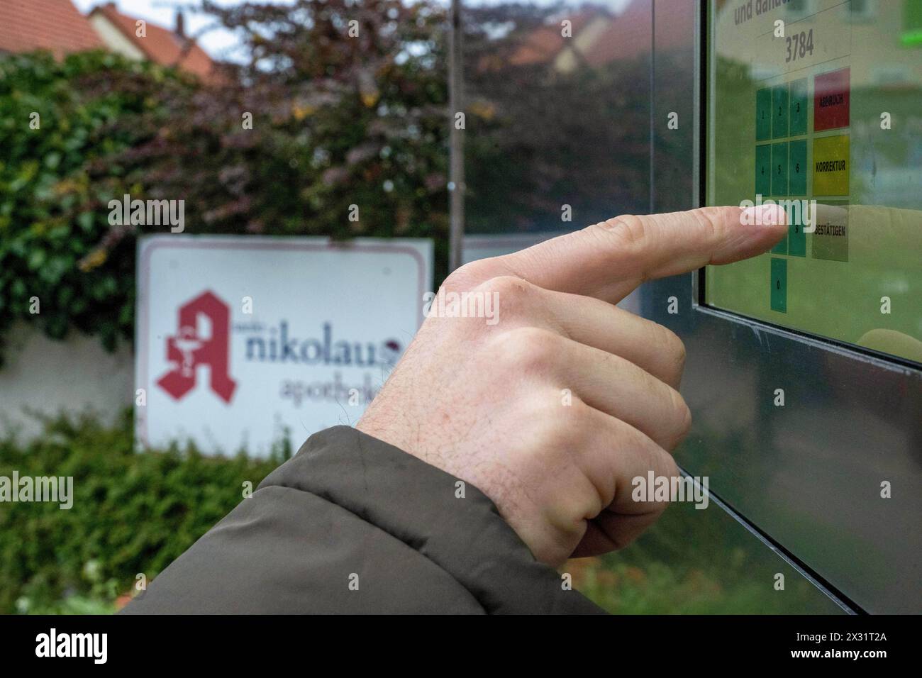 SYMBOL - 24 avril 2024, Bavière, Breitengüßbach : un homme tape un code numérique dans la machine de ramassage à l'extérieur d'une pharmacie pour récupérer les médicaments précommandés en dehors des heures d'ouverture. De plus en plus de pharmacies se tournent vers l’automatisation. Photo : Pia Bayer/dpa Banque D'Images