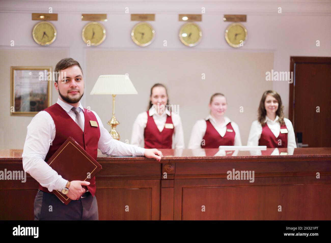 Réceptionnistes - un homme, trois femmes au comptoir pour les clients à l'hôtel, Banque D'Images