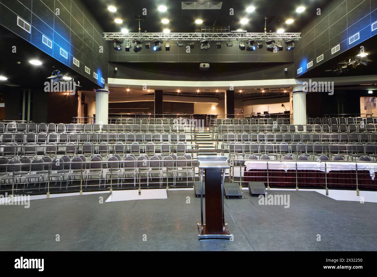 Présentoir et table de documents sur scène et rangées de sièges dans la salle de concert vide. Banque D'Images