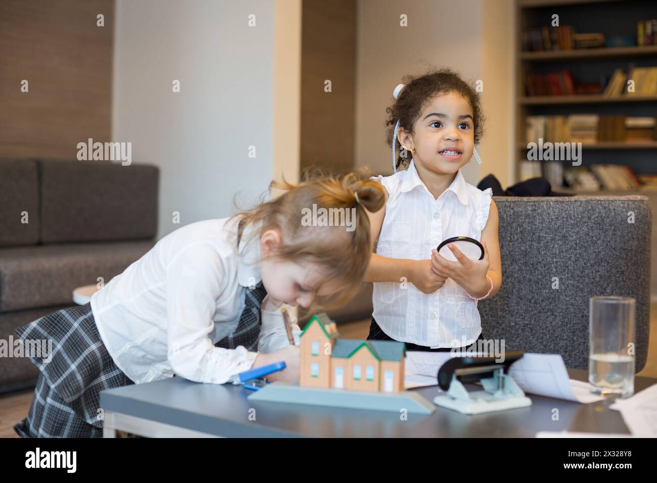 Deux petites filles en costumes d'affaires avec jouet et papeterie dans un centre d'affaires Banque D'Images