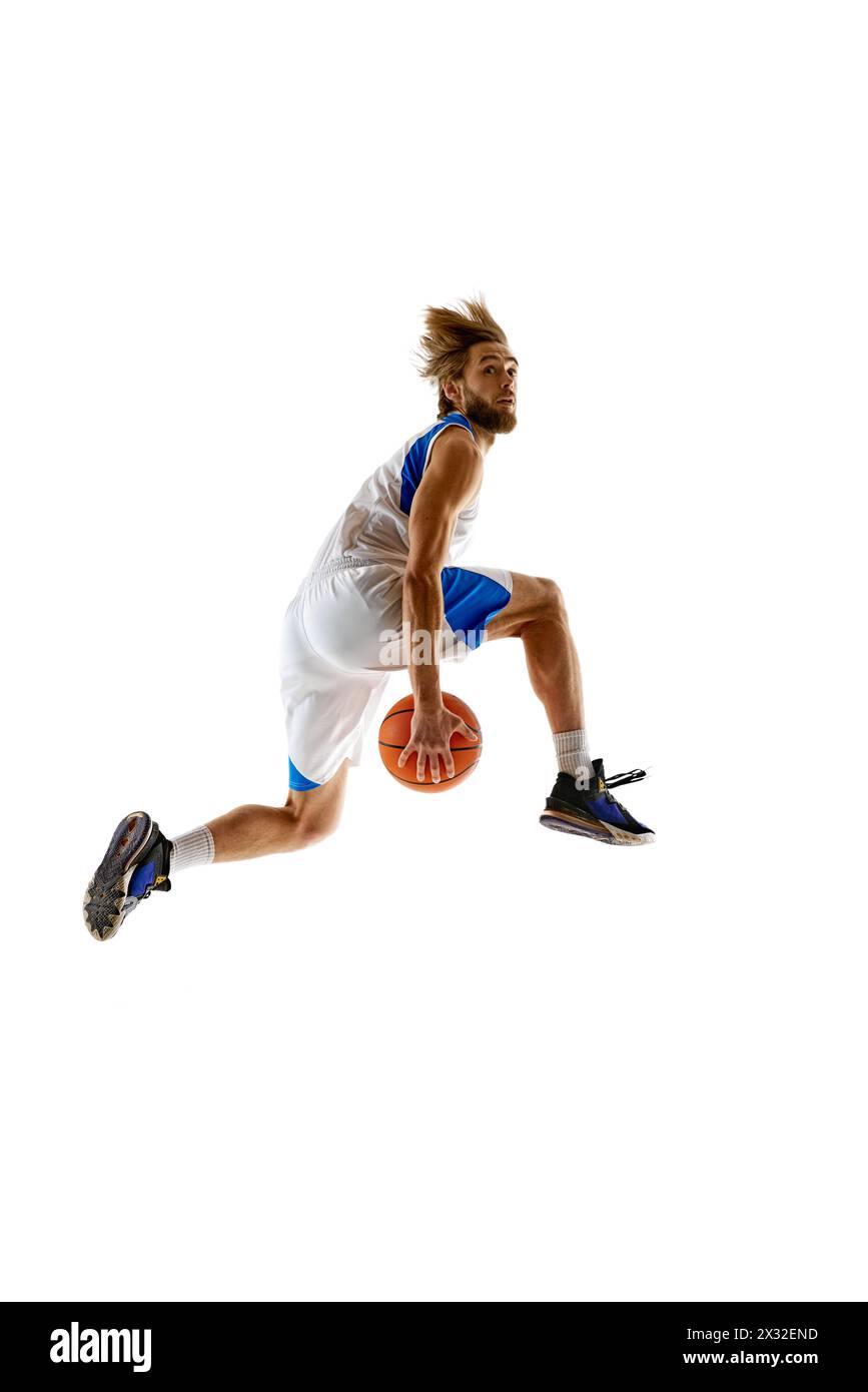 Image dynamique de l'entraînement d'un jeune joueur de basket-ball, sautant dans les airs pour un puissant slam dunk, mettant en valeur l'athlétisme et la force, isolé sur blanc Banque D'Images