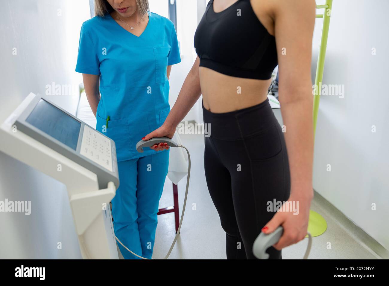 Un praticien de la santé assiste une femme avec un test de composition corporelle à l'aide d'un équipement de pointe. Banque D'Images