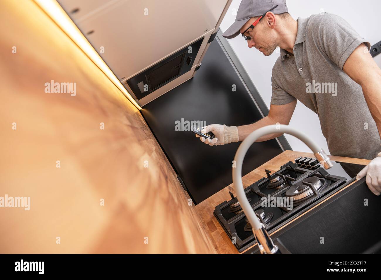 Un homme dans les années 40 testant l'éclairage LED de cuisine à l'aide de la télécommande. Thème de rénovation de cuisine. Banque D'Images