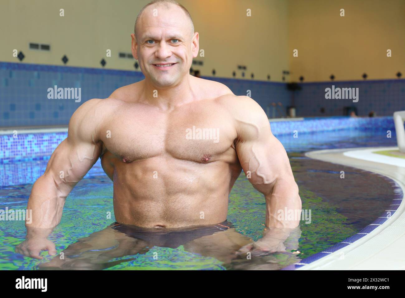 Happy bodybuilder se tient dans l'eau pure de la piscine de la salle de gym Banque D'Images