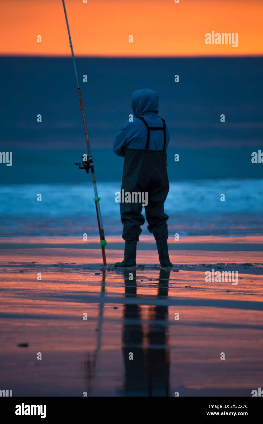 Pescador en la playa al atardecer Banque D'Images
