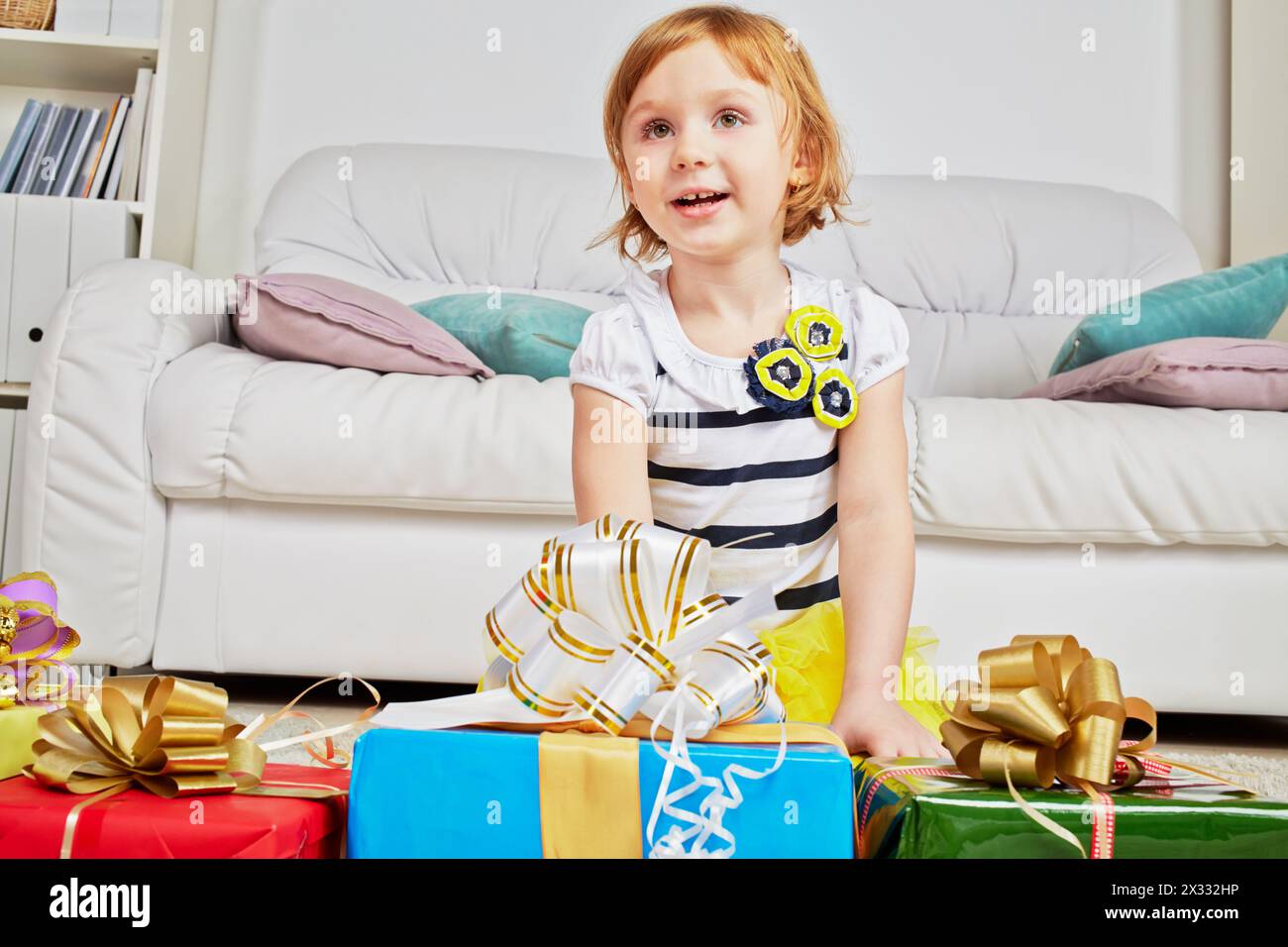 Portrait de la petite fille assise sur les genoux sur la moquette avec des boîtes cadeaux Banque D'Images