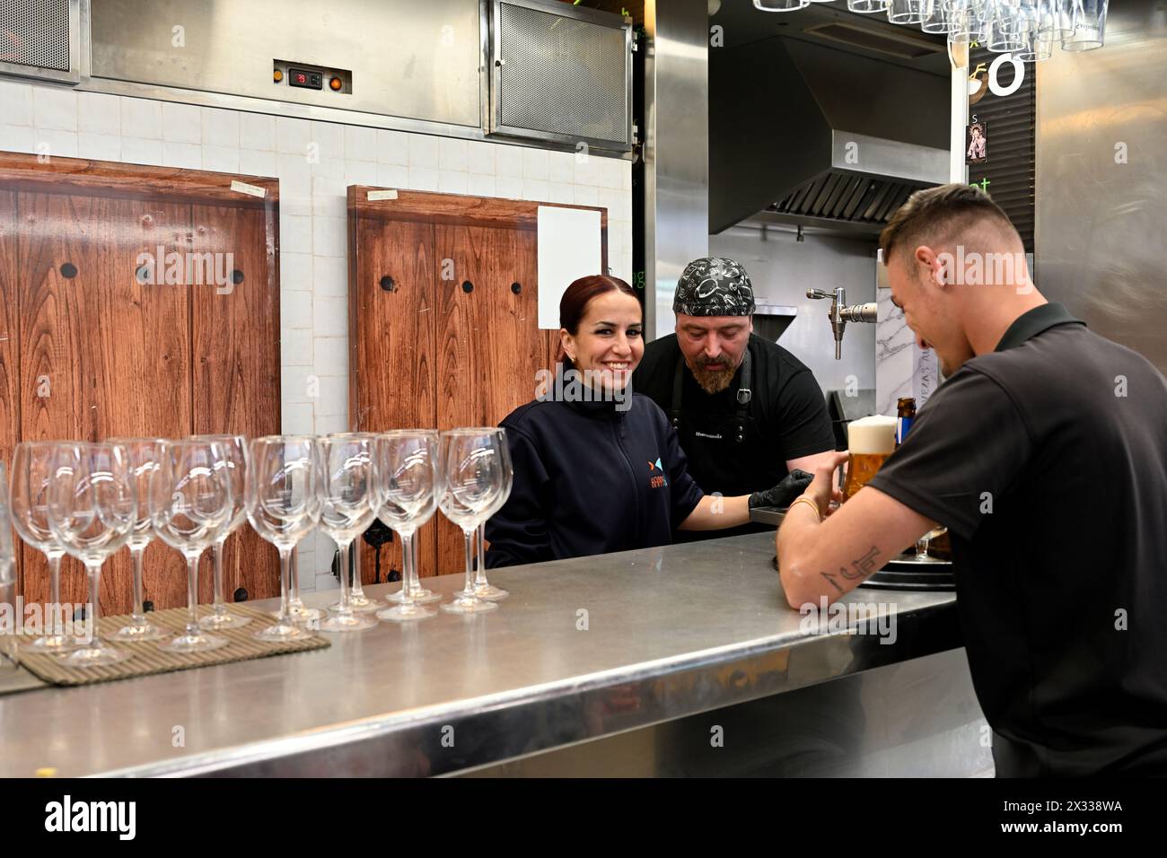 Pub intérieur, bar avec personnel servant, verres sur le comptoir et client avec bière Banque D'Images