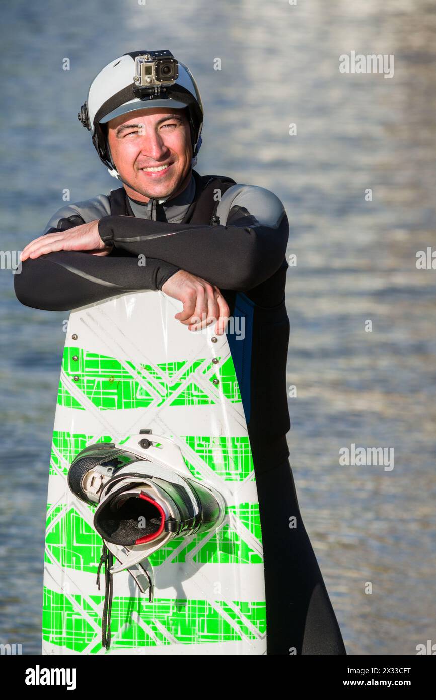 Wakeboarder masculin posant avec sa planche Banque D'Images