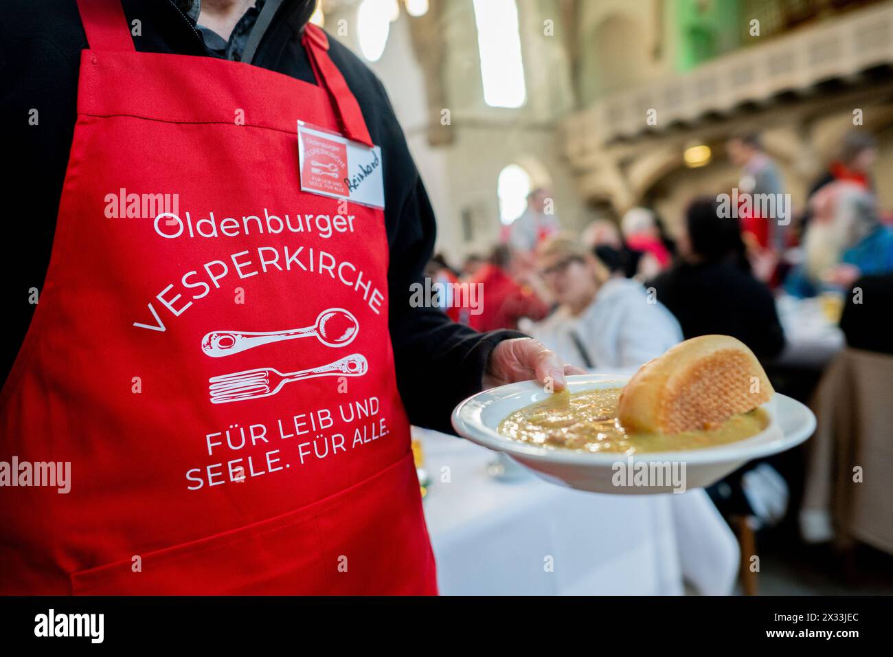 Oldenburg, Allemagne. 18 avril 2024. Un bénévole de l'organisation de secours Johanniter distribue une partie de la soupe aux pois dans l'église de garnison dans le cadre de la Vesperkirche. Une fois par semaine, la Johanniter-Hilfsgemeinschaft à Oldenbourg organise la Vesperkirche pour les personnes dans le besoin. L’offre est rendue possible par de nombreuses institutions et entreprises de soutien. Crédit : Hauke-Christian Dittrich/dpa/Alamy Live News Banque D'Images