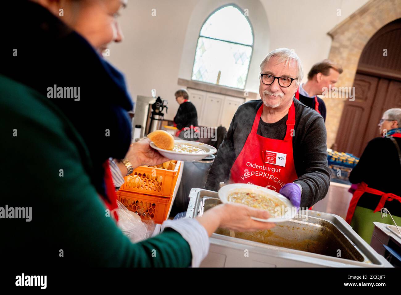 Oldenburg, Allemagne. 18 avril 2024. Des bénévoles de l'organisation de secours Johanniter distribuent de nombreuses portions de soupe de pois dans l'église de garnison dans le cadre de la Vesperkirche. Une fois par semaine, la Johanniter-Hilfsgemeinschaft à Oldenbourg organise la Vesperkirche pour les personnes dans le besoin. L’offre est rendue possible par de nombreuses institutions et entreprises de soutien. Crédit : Hauke-Christian Dittrich/dpa/Alamy Live News Banque D'Images