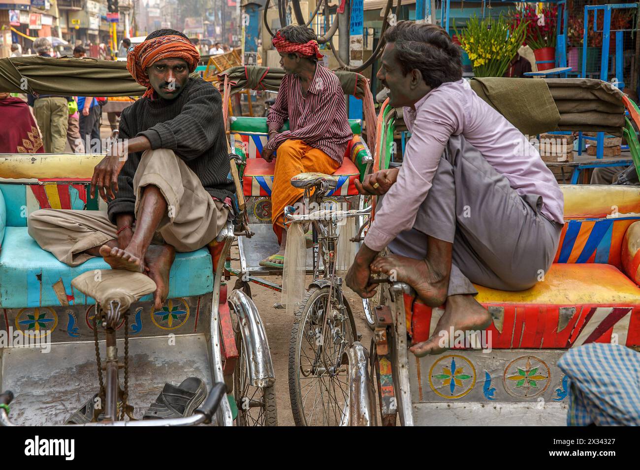 Trois chauffeurs de pousse-pousse à vélo stationnés discutant à Varanasi, en Inde Banque D'Images