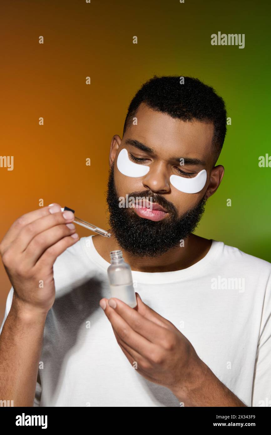 Beau jeune homme appliquant des patchs oculaires pour sa routine de soins de la peau. Banque D'Images