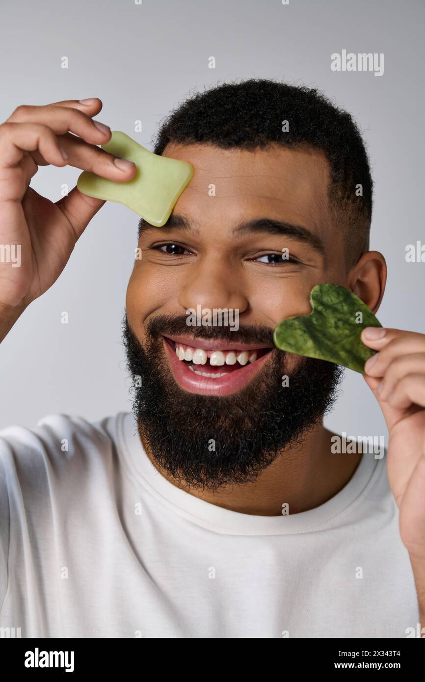 Afro-américain attrayant homme tient gua Sha pour la routine de soins de la peau. Banque D'Images