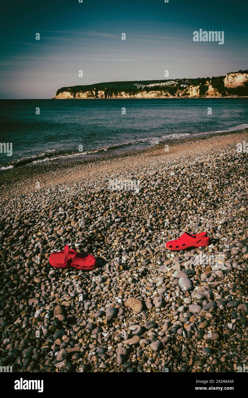 Sabots de plage rouge sur la plage de galets de la côte jurassique, Devon Banque D'Images