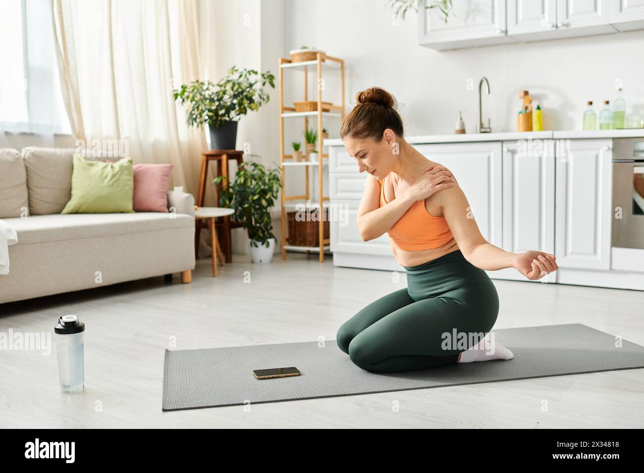 Femme d'âge moyen s'entraîne sur un tapis de yoga dans un salon confortable. Banque D'Images