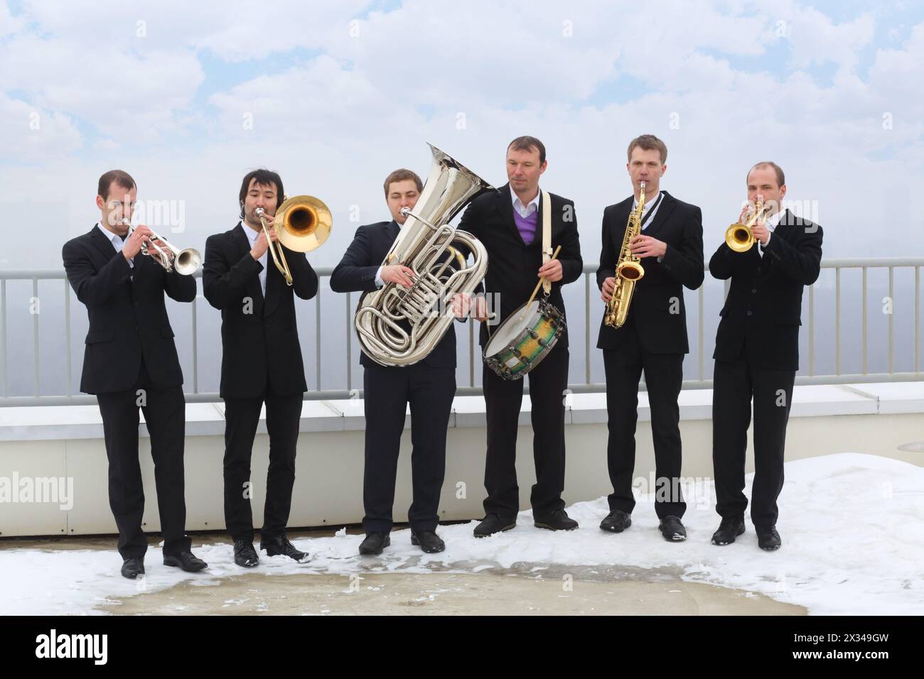 Brass band de six musiciens en costumes jouent de la musique sur le toit d'un grand bâtiment le jour d'hiver Banque D'Images