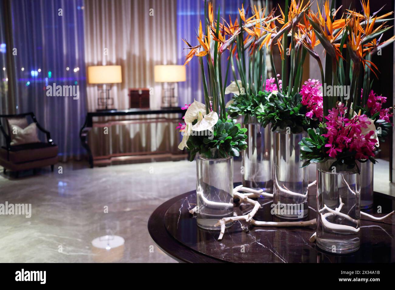 Belles fleurs dans des vases en verre sur table dans une pièce vide le soir Banque D'Images