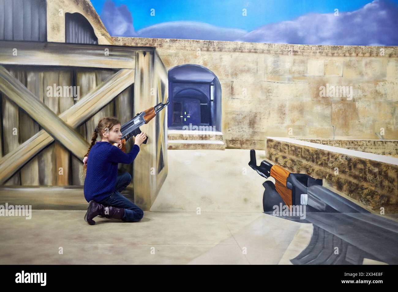 MOSCOU, RUSSIE - Mar 24, 2015 : fille (avec autorisation du modèle) avec Machinegun se cache derrière une boîte en bois dans Optical illusions Museum à VDNKh. Banque D'Images