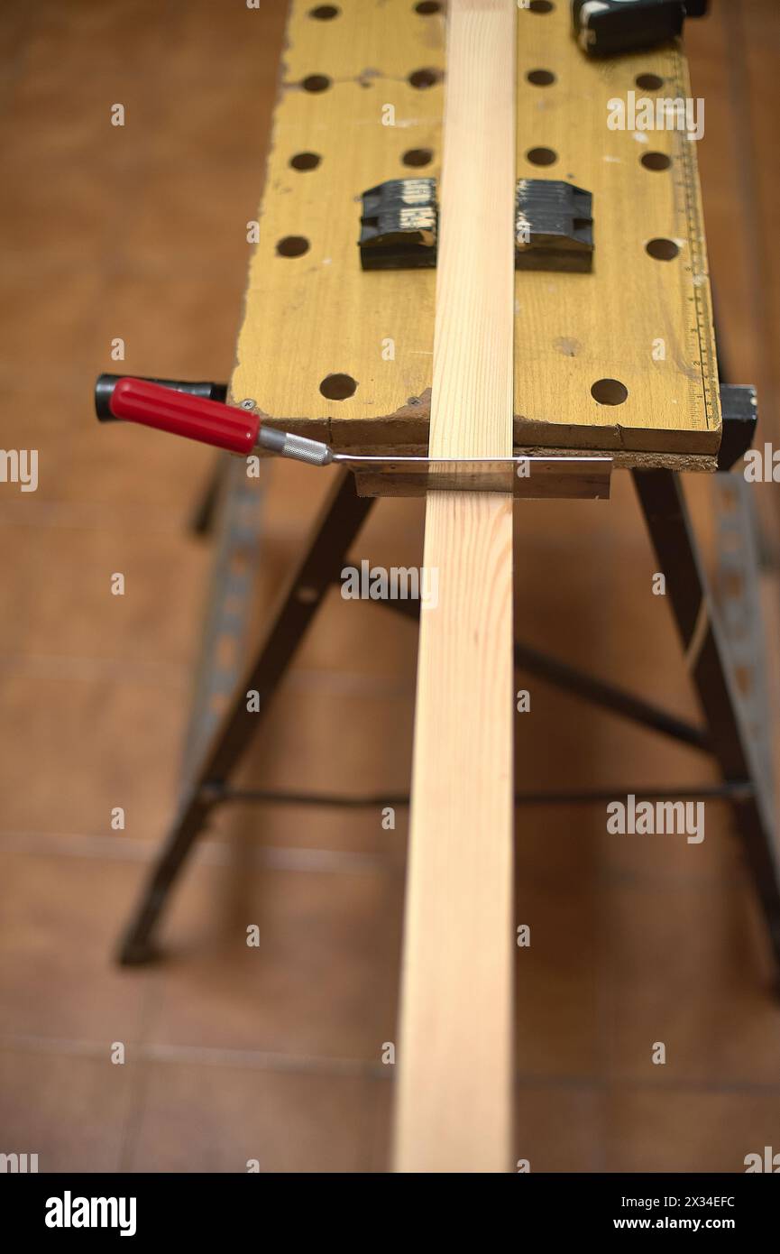 Gros plan d'une scie coupant une planche de bois, montrant la précision et l'habileté en menuiserie. Banque D'Images