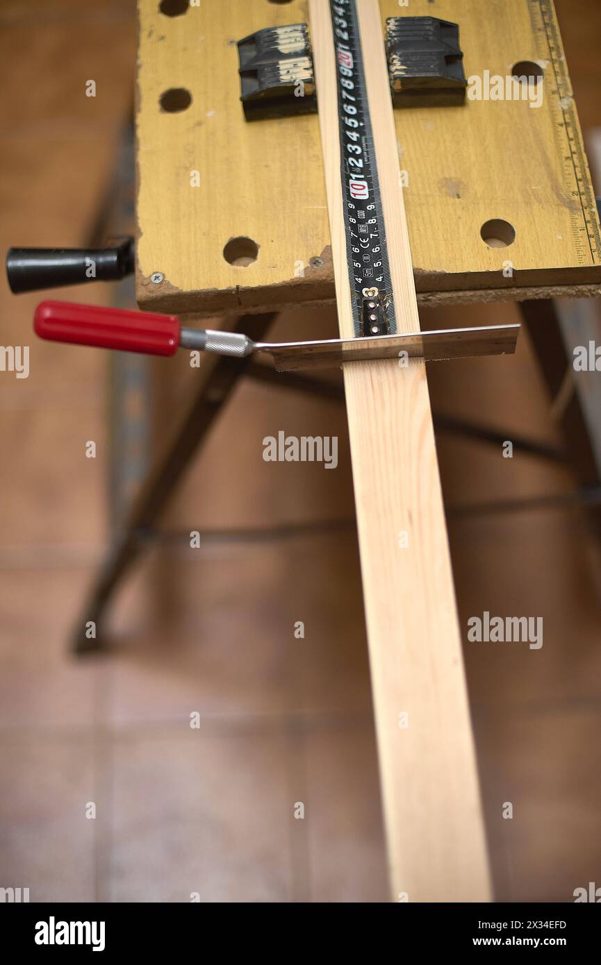 Image d'une scie et d'un ruban à mesurer dans un atelier de menuiserie, capturant le processus de coupe du bois Banque D'Images