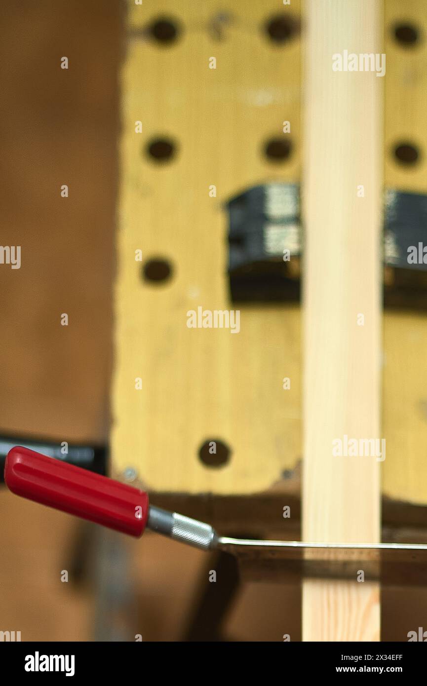 Image détaillée d'une scie à main coupant une planche de bois, soulignant la dextérité et la précision dans l'artisanat de la menuiserie. Banque D'Images