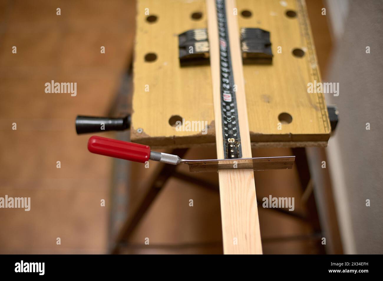 Vue détaillée d'une scie coupant du bois sur un établi, soulignant l'essence du travail de menuiserie Banque D'Images