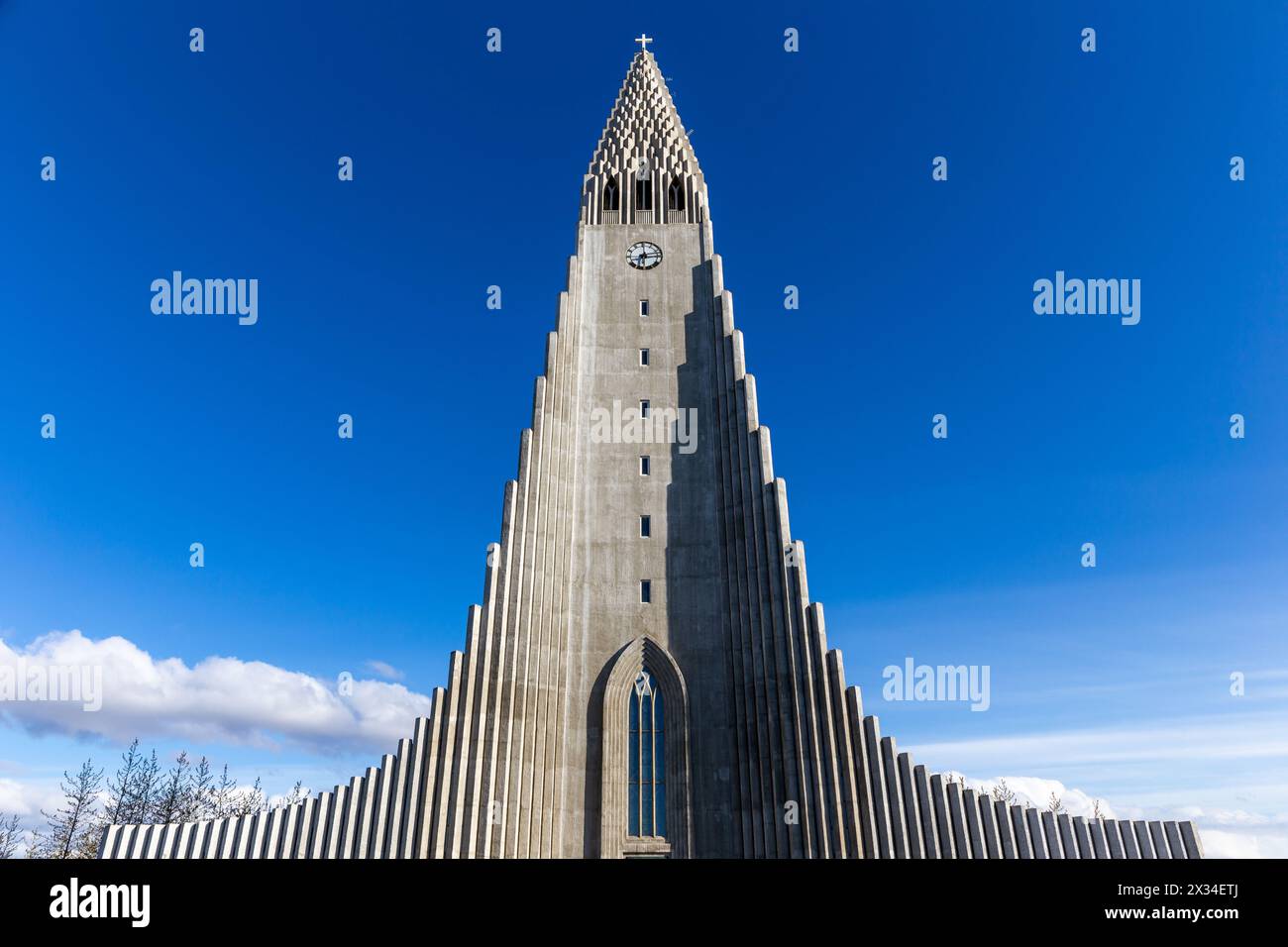 Église moderniste Hallgrimskirkja ressemblant à des colonnes de basalte à Reykjavik, Islande, beffroi moderne et ailes contre le ciel bleu clair, vue symétrique. Banque D'Images