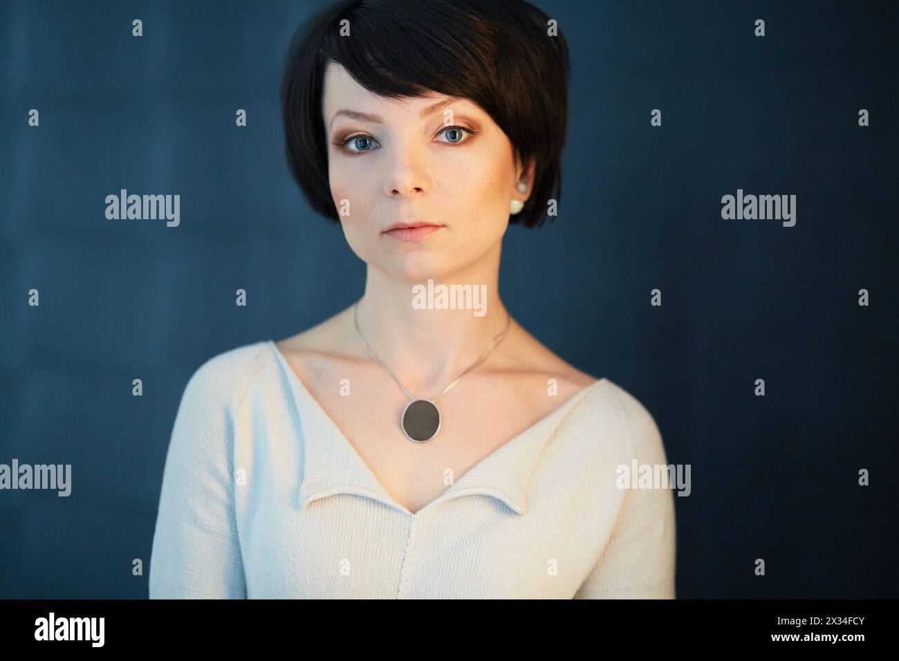 Portrait d'épaule d'une femme aux cheveux foncés en robe tricotée blanche. Banque D'Images