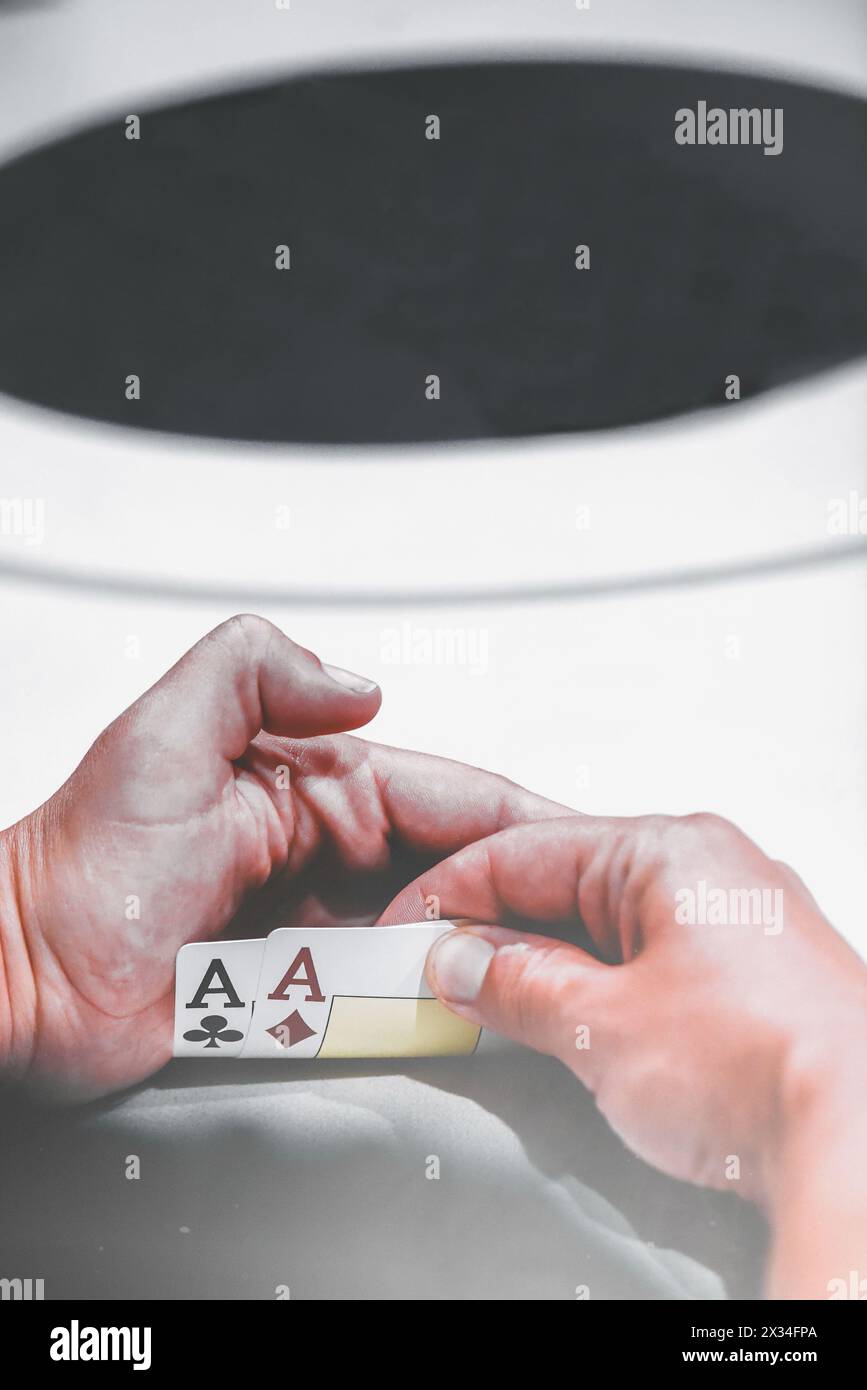 Vue rapprochée d'une main de joueur de poker tenant secrètement une paire d'as, la main de départ la plus forte dans Texas Holdem Banque D'Images