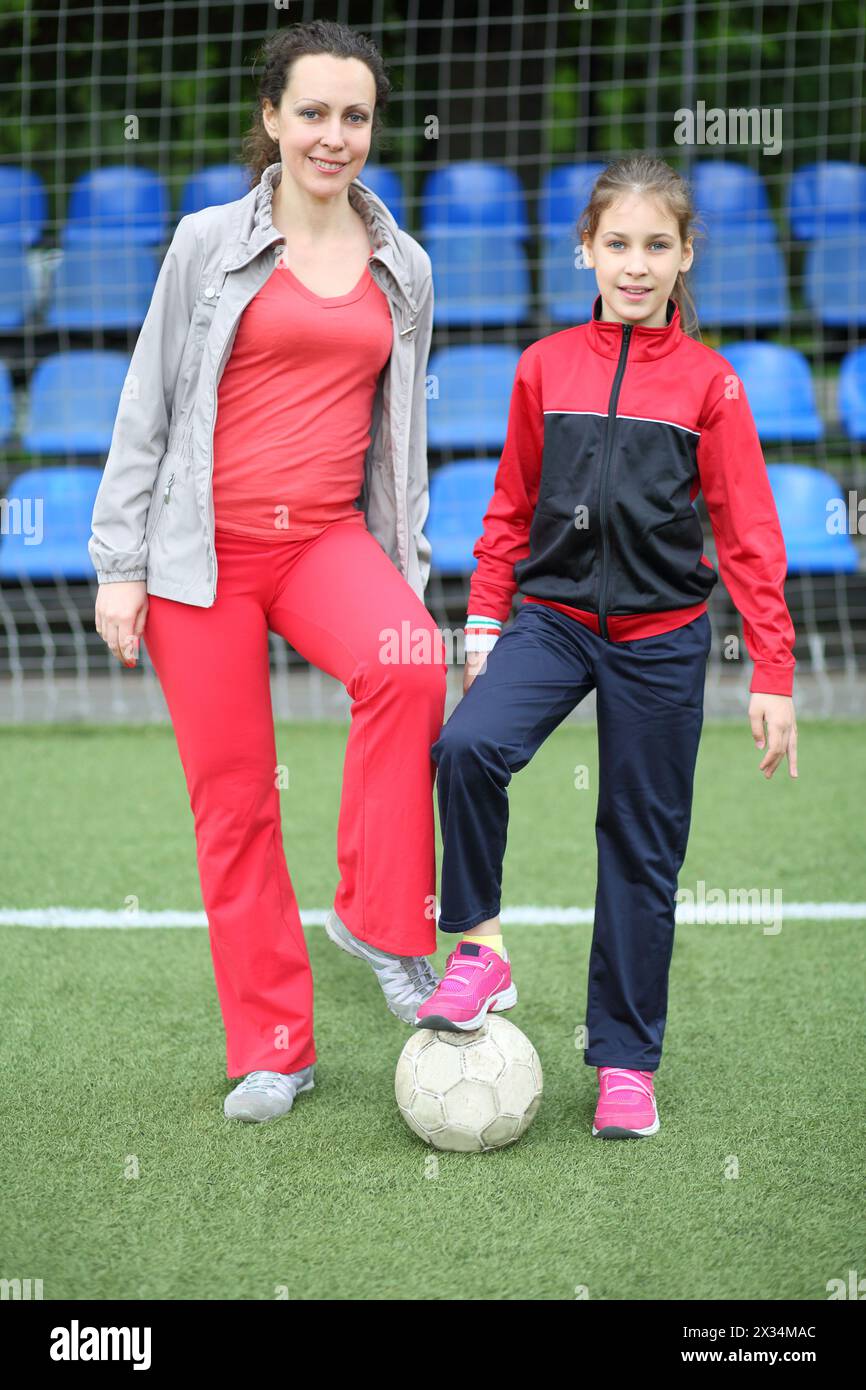 Portrait d'une mère et d'une fille en survêtement et le ballon au stade Banque D'Images