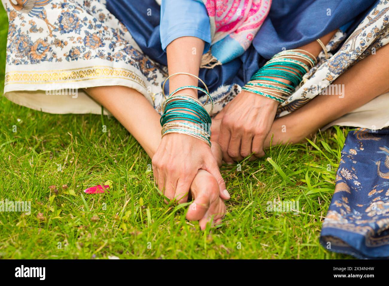 Pieds nus d'une femme indienne en sari lumineux assis sur l'herbe dans le jardin Banque D'Images