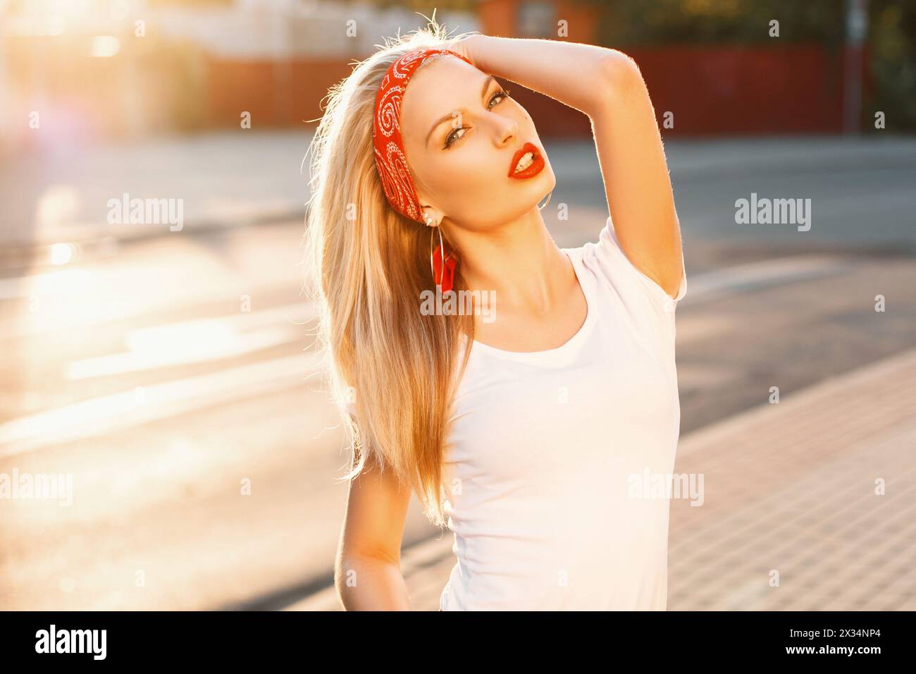 Portrait d'Une jolie fille Hipster avec des lèvres rouges en T-shirt blanc sur la rue au coucher du soleil Banque D'Images