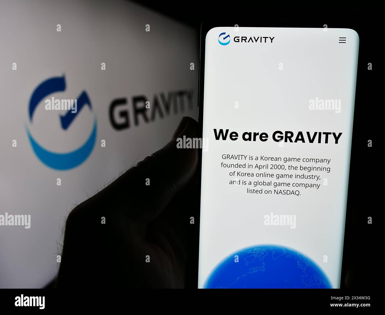 Personne tenant le téléphone portable avec la page Web de la société sud-coréenne de jeux vidéo Gravity Co. Ltd devant le logo. Concentrez-vous sur le centre de l'écran du téléphone. Banque D'Images