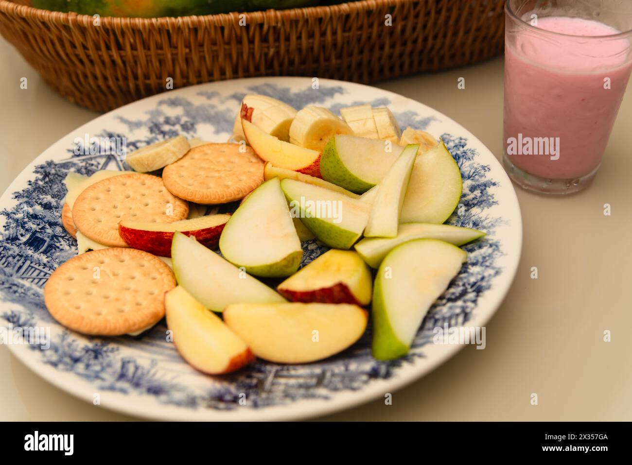 Assiette de petit déjeuner avec banane, pomme, poire, biscuit, fromage et yaourt sur une table. Nourriture saine. Banque D'Images