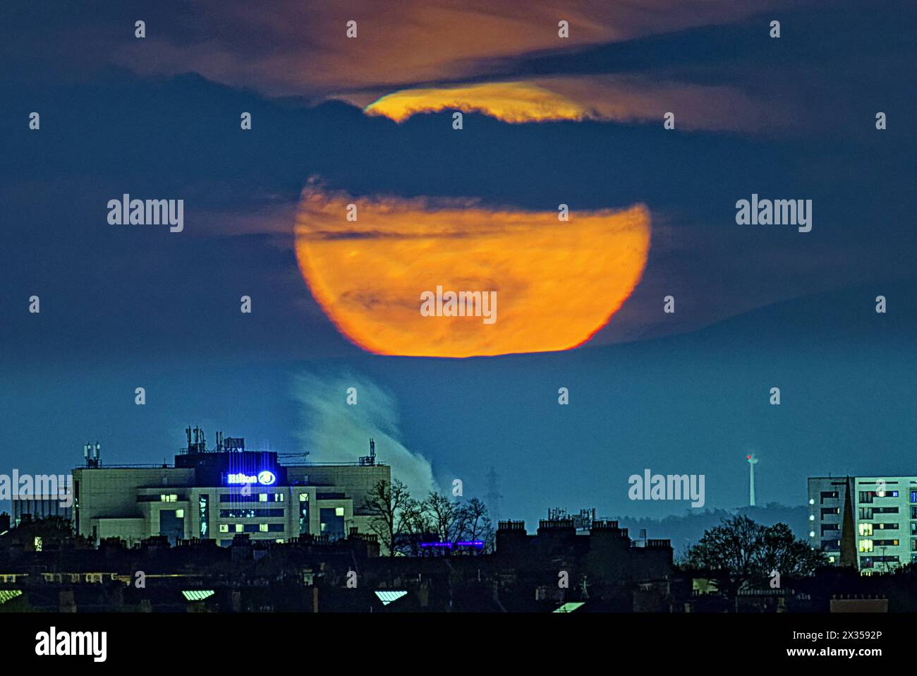 Glasgow, Écosse, Royaume-Uni. 24 avril 2024 : Météo britannique : pleine lune sur la colline de Tinto dans les frontières où les druides ont fait des sacrifices humains devant le Hilton et la fumée de la distillerie de whisky gorbals dans le centre-ville, la pleine Lune d'avril ou la pleine Lune rose est connue sous différents noms tels que la Lune d'herbe germinante, la Lune grandissante et la Lune de poisson. Crédit Gerard Ferry/Alamy Live News Banque D'Images