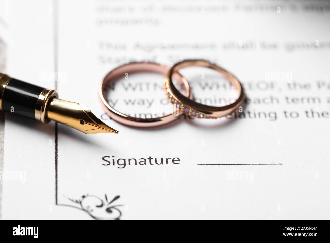 Contrat de mariage, stylo plume et anneaux de mariage sur table, gros plan Banque D'Images