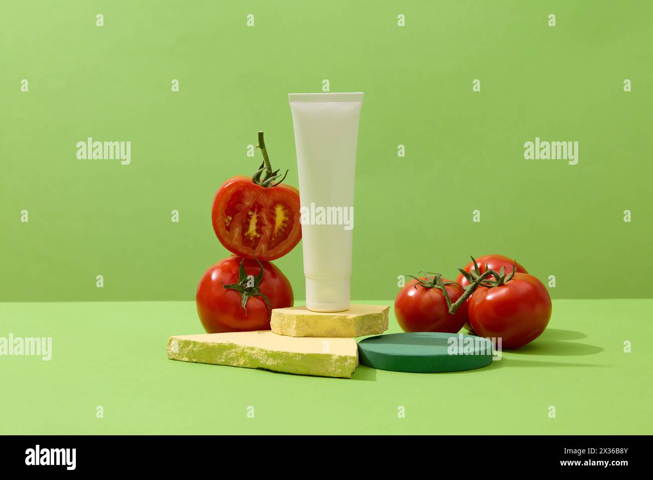 Tube de beauté d'étiquette vierge debout sur des pierres cassées, décoré avec des tomates rouges. L'application de tomates sur le visage peut minimiser et prévenir l'acné Banque D'Images