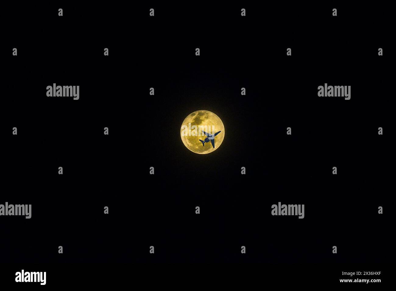 Avion passant par la lune rose le 24 avril 2024. Banque D'Images