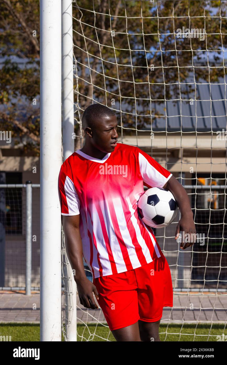 Jeune athlète afro-américain tenant un ballon de football par poteau de but, espace de copie Banque D'Images