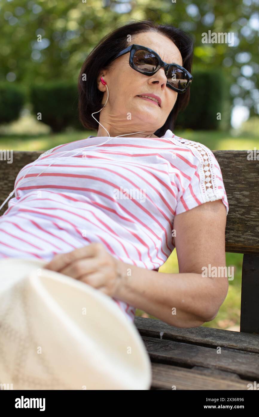 femme âgée se relaxant sur un banc Banque D'Images