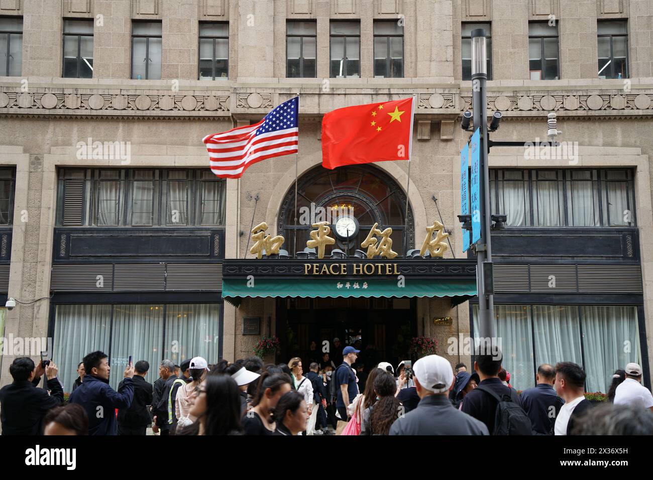 SHANGHAI, CHINE - 25 AVRIL 2024 - le drapeau rouge cinq étoiles de la Chine et le drapeau américain sont accrochés au-dessus de l'entrée de l'hôtel Peace le long de la route de Nanjing Pede Banque D'Images