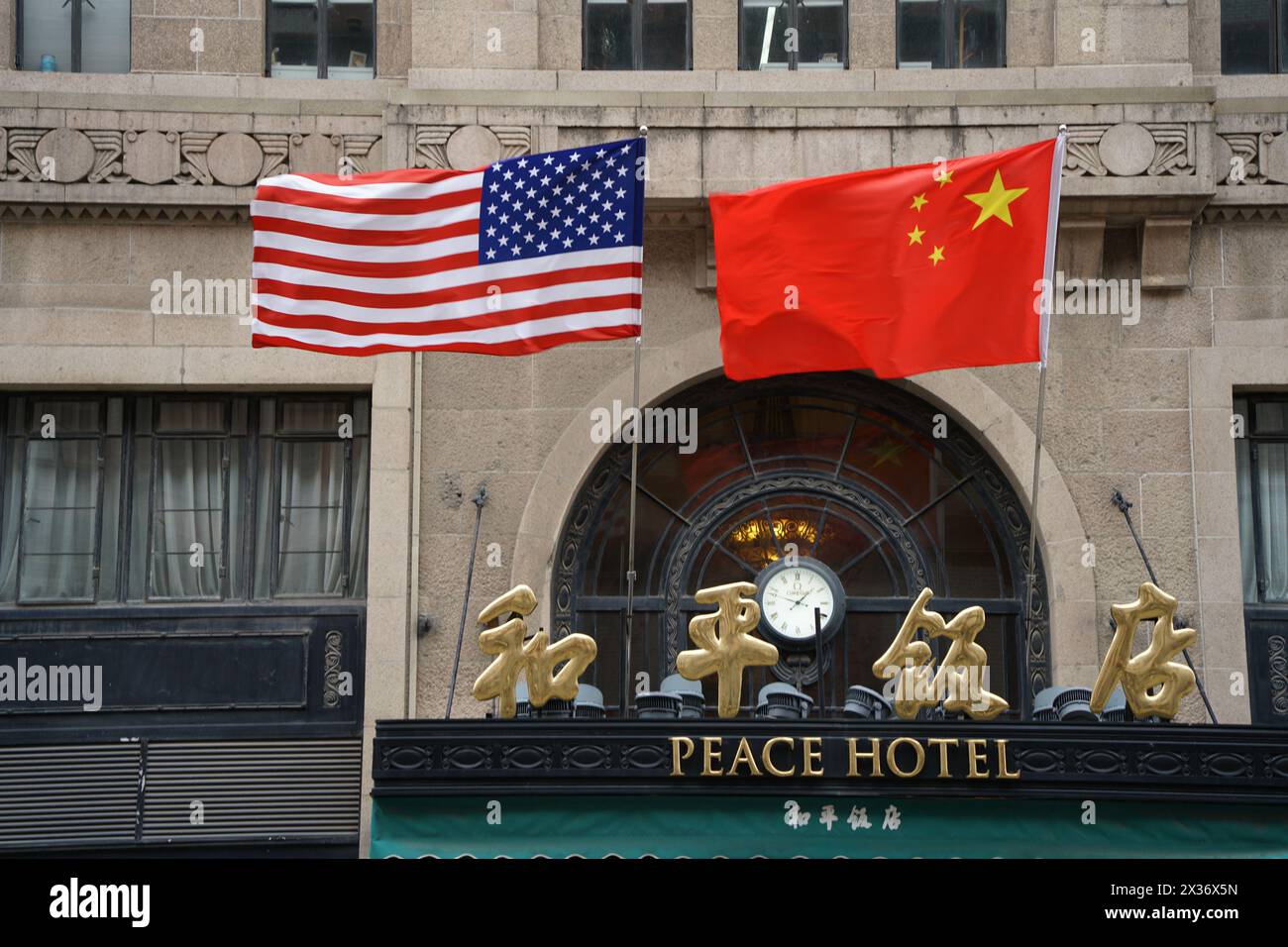 SHANGHAI, CHINE - 25 AVRIL 2024 - le drapeau rouge cinq étoiles de la Chine et le drapeau américain sont accrochés au-dessus de l'entrée de l'hôtel Peace le long de la route de Nanjing Pede Banque D'Images